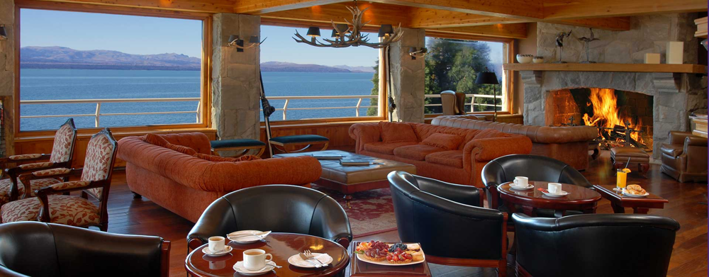 Lobby lounge of Cacique Inacayal, with its fireplace and lake-facing windows: a cozy space to enjoy the view any time of year.